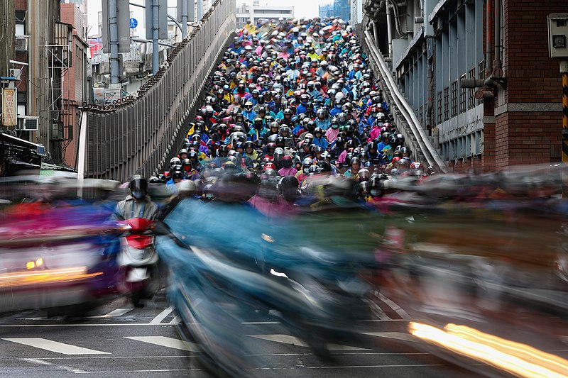 《臺北之晨》半世紀前人力拖板車、嘟嘟車入城的景況不再，現在的臺北橋是機車瀑布與周遭林立的水泥住宅。（source: wikicommons）